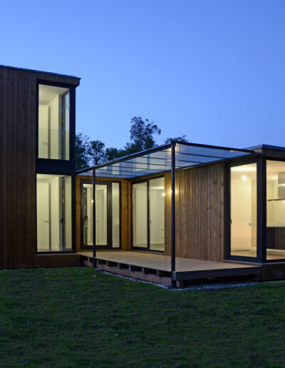 Casa de dos plantas con estructura de hormigón y fachada de madera