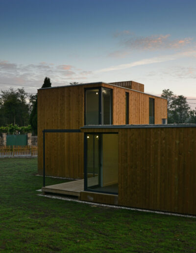 Casa de dos plantas con estructura de hormigón y fachada de madera